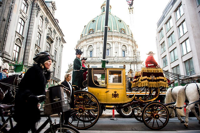 A cyclist is passed by the queen's gold carriage. Photo: Ólafur Steinar Gestsson/Scanpix 