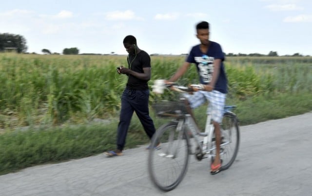 Many of the migrants attempt to kill time by walking or cycling around the area. Photo: TIZIANA FABI / AFP
