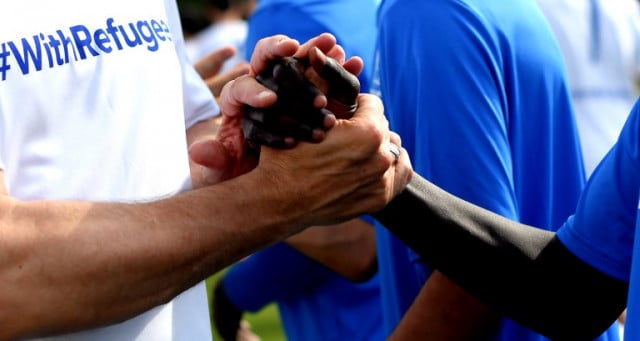 A young refugee (R) shakes hands with a member of a team of former professional footballers prior to the start of their friendly organised by the United Nation's UNHCR in Rome on Saturday. Photo: Tiziana Fabi/AFP
