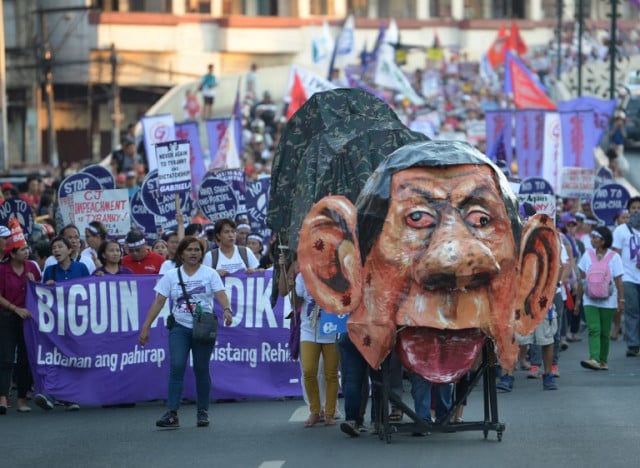 Protesters push a giant effigy depicting Philippine President Rodrigo Duterte as they march toward Malacanang palace during celebration of International Women's Day in Manila on March 8, 2018. The protesters assailed the government of President Rodrigo Duterte on issues ranging from continued violence against women, drug war, tax reform program, and changing of the constitution among others. Photo: TED ALJIBE / AFP