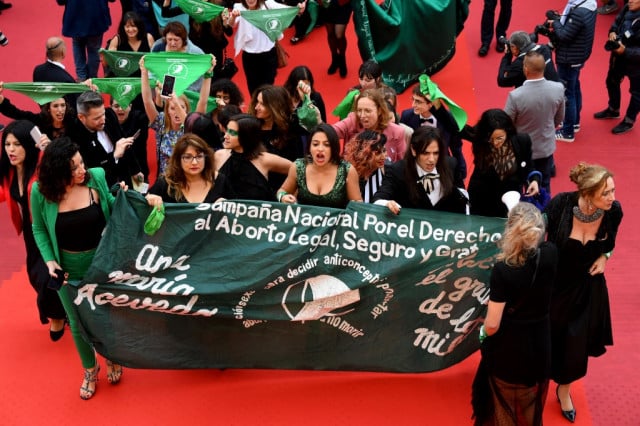 Pro-choice activists march behind a banner and wave scarves of the Argentinian pro-choice movement as they arrive for the screening of the film 