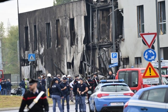 Police and rescue teams outside the office building where a small plane crashed in the Milan suburb of San Donato. 