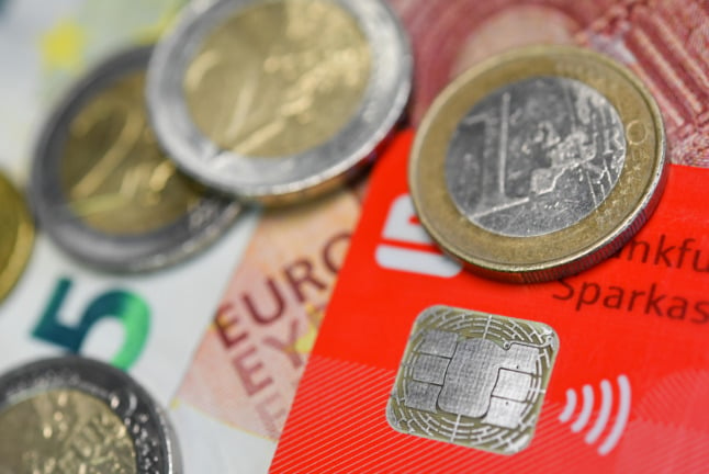Cash lies across a German bank card.