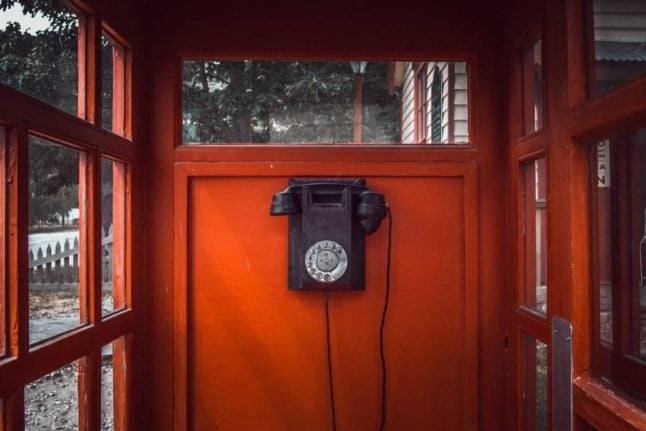 A rotary phone in a red telephone box