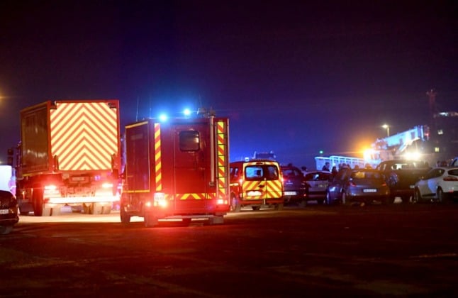 Emergency vehicles, with blue lights flashing at Calais harbour after a boat carrying migrants from France to UK sank, killing dozens
