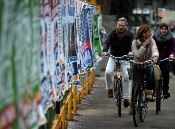 People cycle by billboards in Castel Gandolfo, south of Rome.