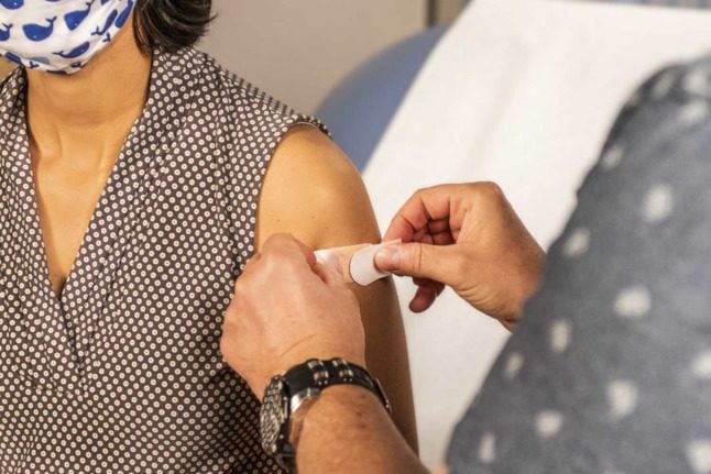 A person has their arm covered with a band aid after receiving a vaccination