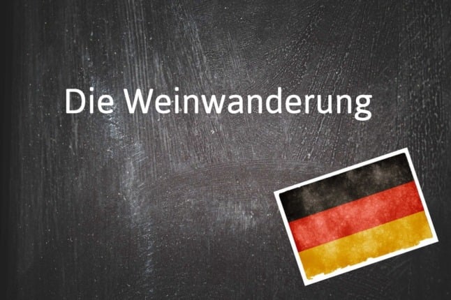 A blackboard shows the German word 'die Weinwanderung'.