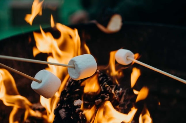 White marshmallows toast over a fire