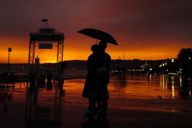 A silhouette of a couple, carrying an umbrella, as they walk along the Promenade des Anglais, in Nice, France.