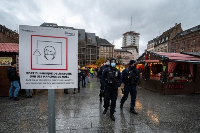 Police officers patrol the Strasbourg Christmas market, armed with machine guns, to enforce French mask wearing rules.