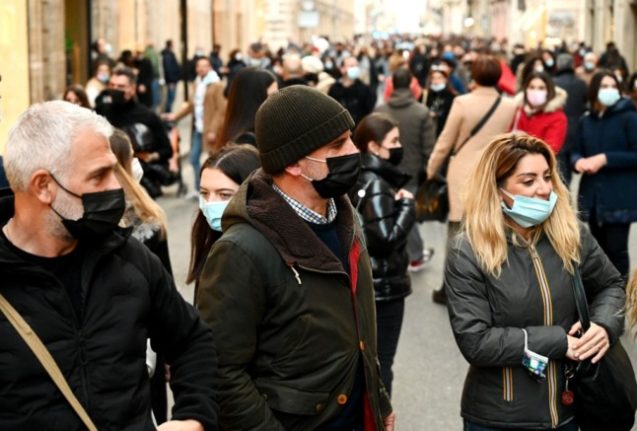 People wear protective face masks as they walk along the Via del Corso main shopping street in central Rome, Italy