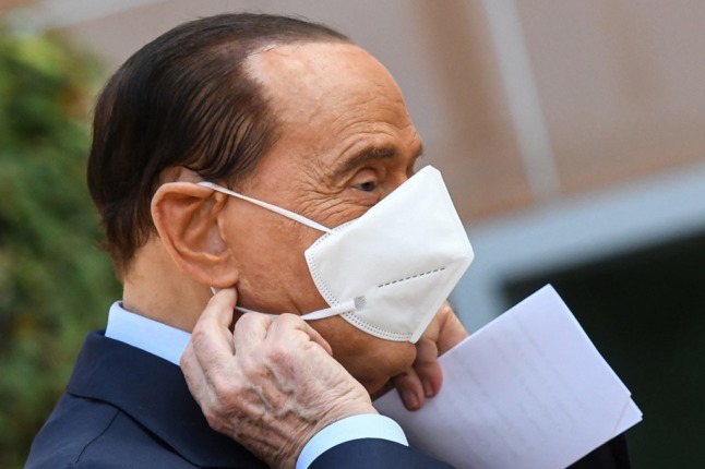 Former Italian prime minister Silvio Berlusconi takes off his face mask as he prepares to address the media, as he leaves the San Raffaele Hospital in Milan on September 14, 2020 after he tested posititive for coronavirus and was hospitalized since September 3