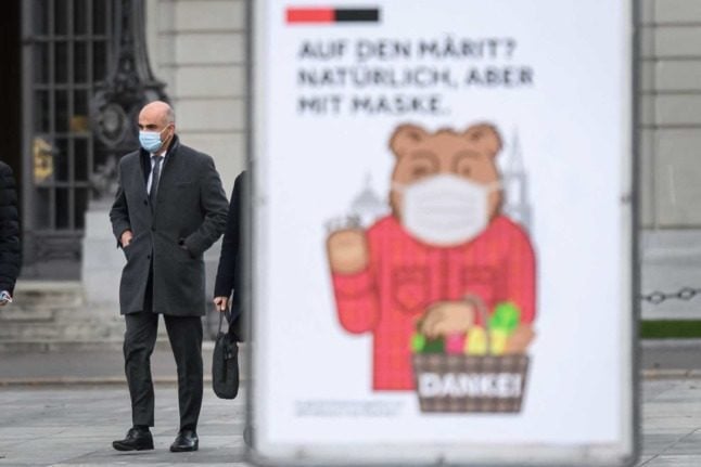 Swiss Health Minister Alain Berset walks past a poster reminding people to wear masks. Photo: Fabrice COFFRINI / AFP