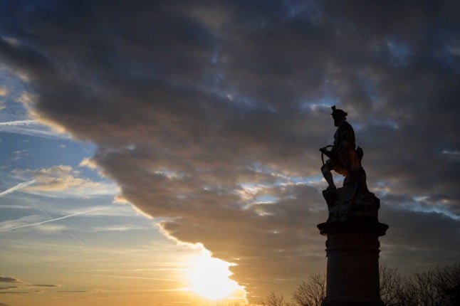 This photograph taken on December 23, 2021 shows a statue representing the 14th century Swiss folk hero Wilhelm Tell holding his crossbow in silhouette at sunset in Lausanne.