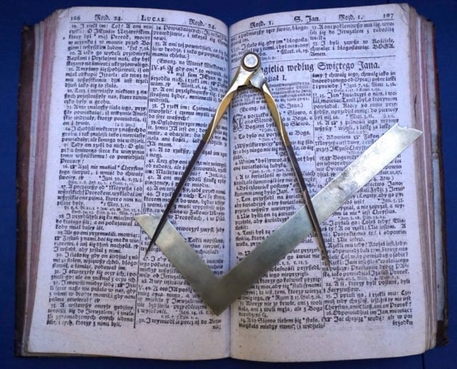 A square (bottom) and a compass, symbols of Freemasonry, are displayed on a book