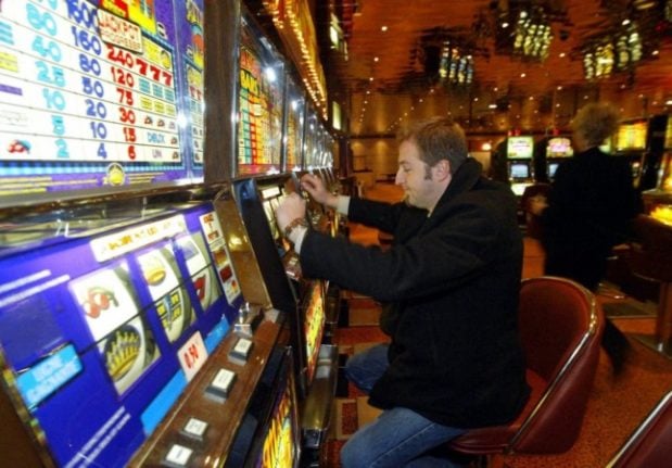 A man enters coins into a slot machine in the Saint-Amand-les-Eaux casino in northern France. 