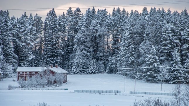 Pictured are powerlines running past a snow covered cabin.